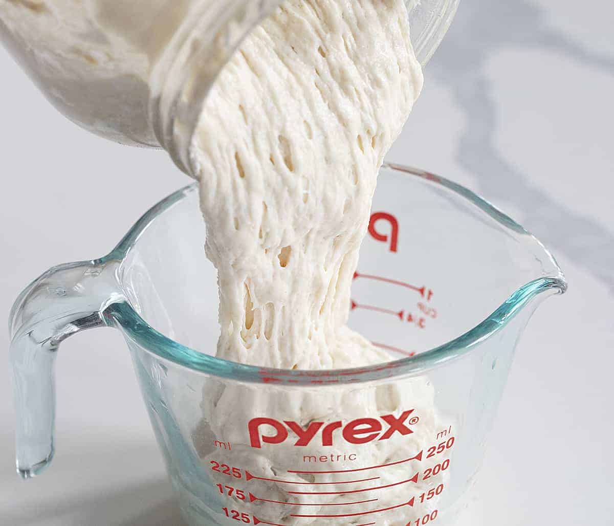Pouring active sourdough starter into measuring glass