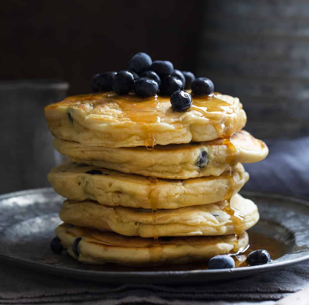 Blueberry Sourdough Pancakes are light and fluffy pancakes that you can make in minutes using your sourdough starter. Pancakes, Blueberry Pancakes, Blueberry Sourdough Pancakes, How to Make Sourdough Pancakes, Sourdough Starter Recipes, Breakfast, i am homesteader, iamhomesteader, pancake recipe Blueberry Sourdough Pancakes Stacked on Plate with Blueberries