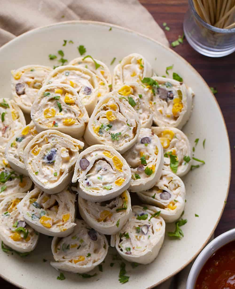 Mexican inspired Tortilla Pinwheels are flour tortillas that are wrapped around a cheesy mixture loaded with chiles, green onions, black beans, corn, jalapeno peppers, and taco seasoning. Tortilla Pinwheels, Mexican Pinwheels, Pinwheel Recipes, Appetizers, i am homesteader, iamhomesteader, recipes Tortilla Pinwheels on Plate