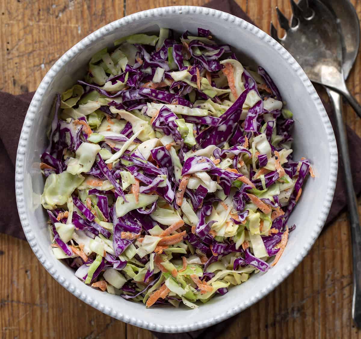 This Coleslaw recipe is a side dish made with freshly shredded cabbage and carrots tossed in mayonnaise and buttermilk-based tangy dressing. BBQ recipes, campfire recipes, coleslaw recipe, vinegar based coleslaw, creamy coleslaw, how to make coleslaw, side dish, fish taco coleslaw, slaw, recipes, i am homesteader, iamhomesteader Bowl of Creamy Coleslaw