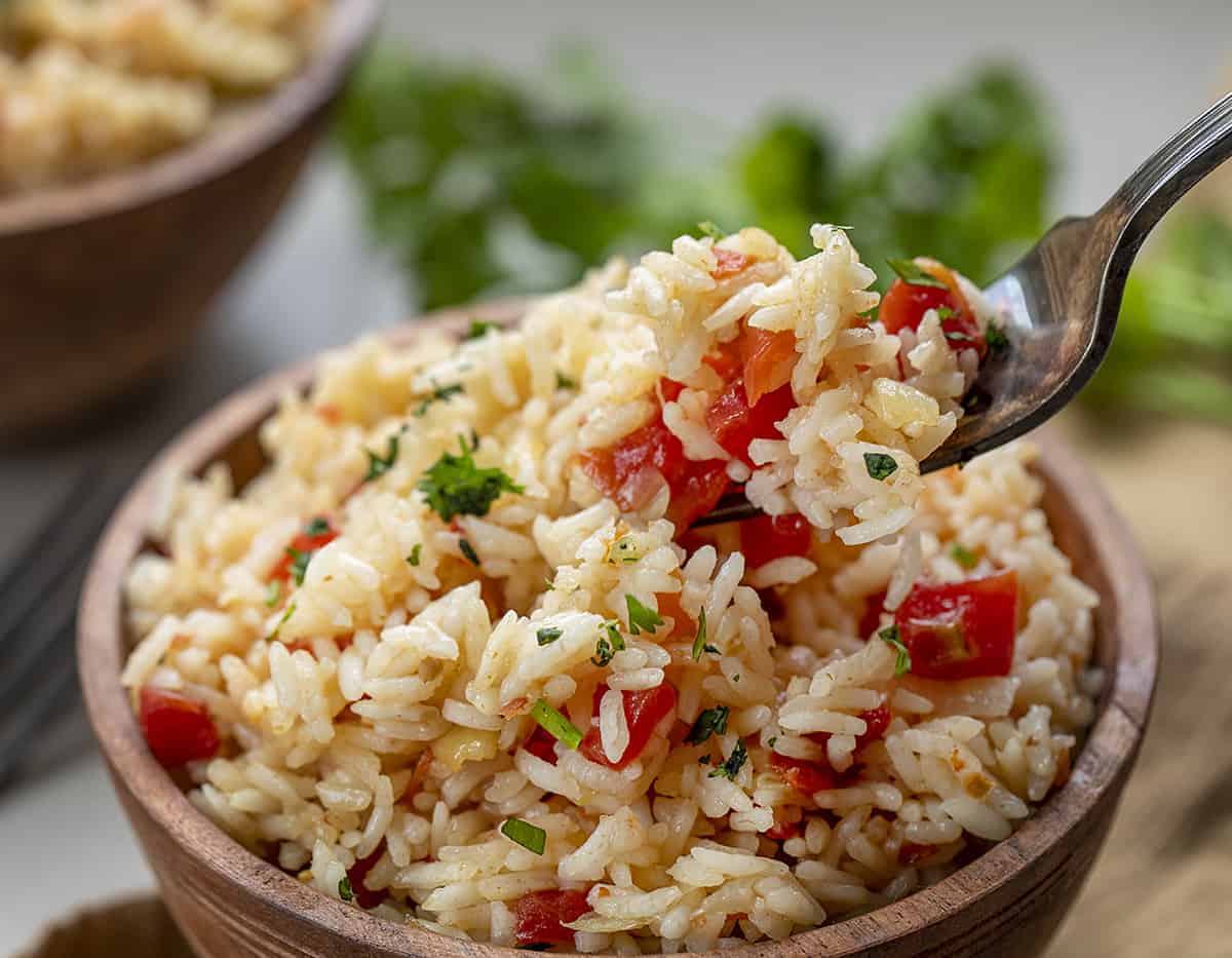Mexican Rice is white rice cooked with onions and garlic in chicken broth with diced tomatoes and seasonings. Side Dish, Mexican Rice, Spanish Rice, Red Rice, Difference between spanish rice and mexican rice, recipes, i am homesteader, iamhomesteader Fork Picking up a Bite of Spanish Rice