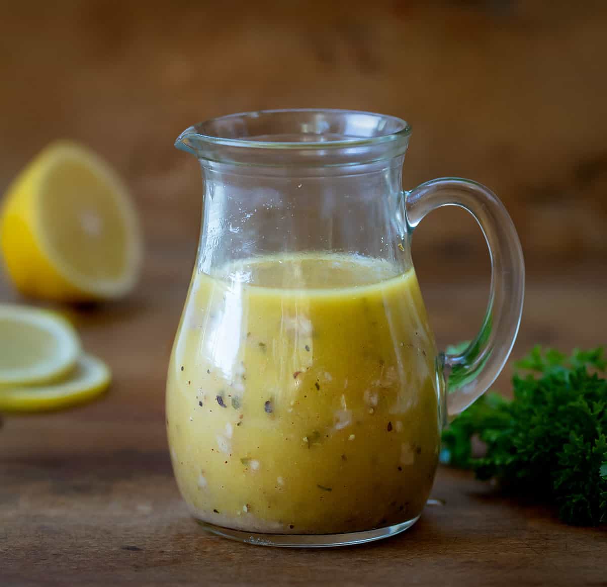 Make your own Homemade Greek Vinaigrette at home with this easy recipe. Control the ingredients and enjoy the tangy and flavorful dressing on your salads! Ready in 5 minutes! Bottle of Homemade Greek Vinaigrette on a wooden table.