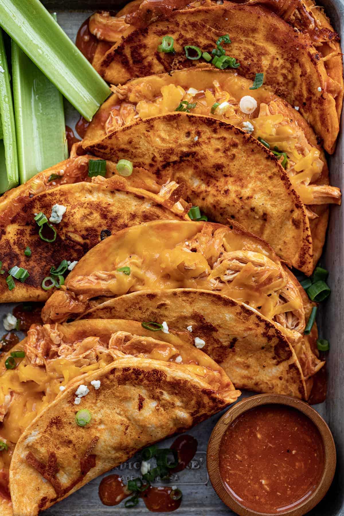 Buffalo Chicken Tacos on a tray from overhead with sauce and celery.