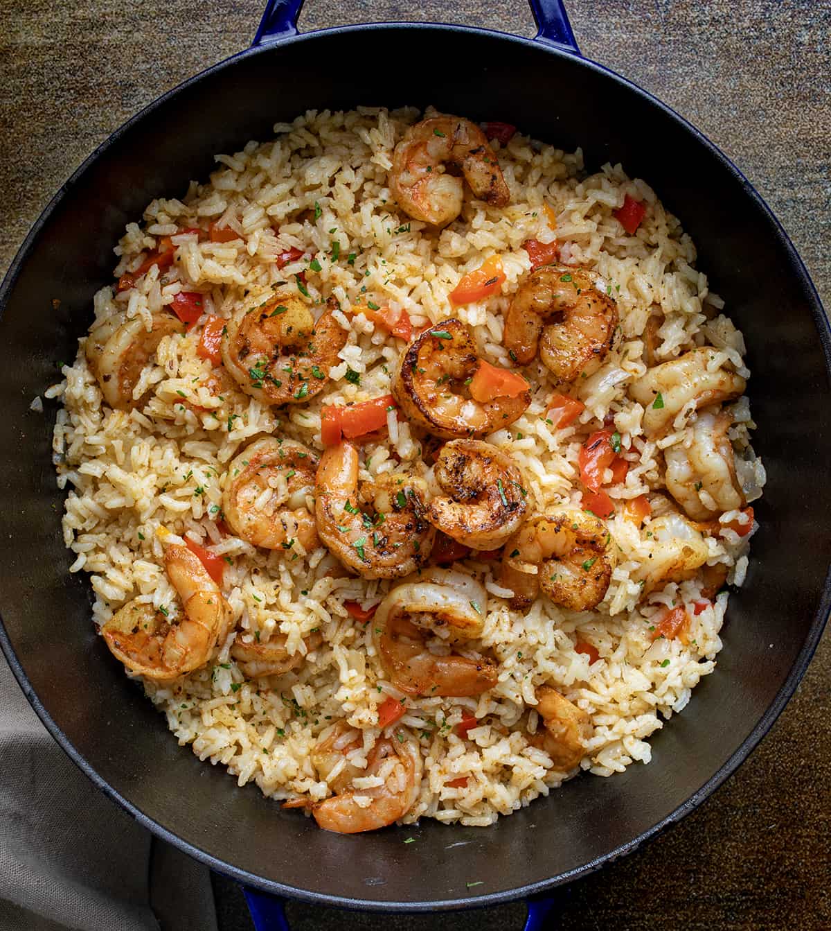Cajun Shrimp and Rice is a delectable dish featuring Cajun shrimp, flavorful rice, and a zesty lemon twist for an extra burst of flavor! It's a spicy, satisfying, and incredibly delicious dish that's sure to become a family favorite. Pan of Cajun Shrimp and Rice on a Wooden Table from Overhead.