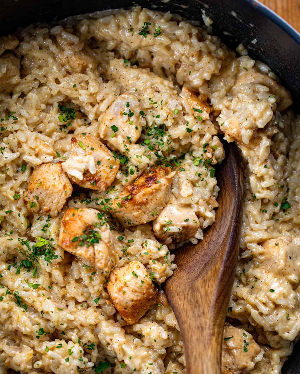 Cajun Chicken and Rice is a rich and spicy dish that consists of a blend of Cajun spices, a creamy sauce, and tender chicken, all mixed with seasoned rice. It does have a kick to each bite (well, according to my taste buds), but if you love a flavorful dish with a little bit of heat from Cajun seasoning, you will love it! It also tastes just as delicious when reheated if you have any leftovers. Close up of Cajun Chicken and Rice in a pot from overhead.