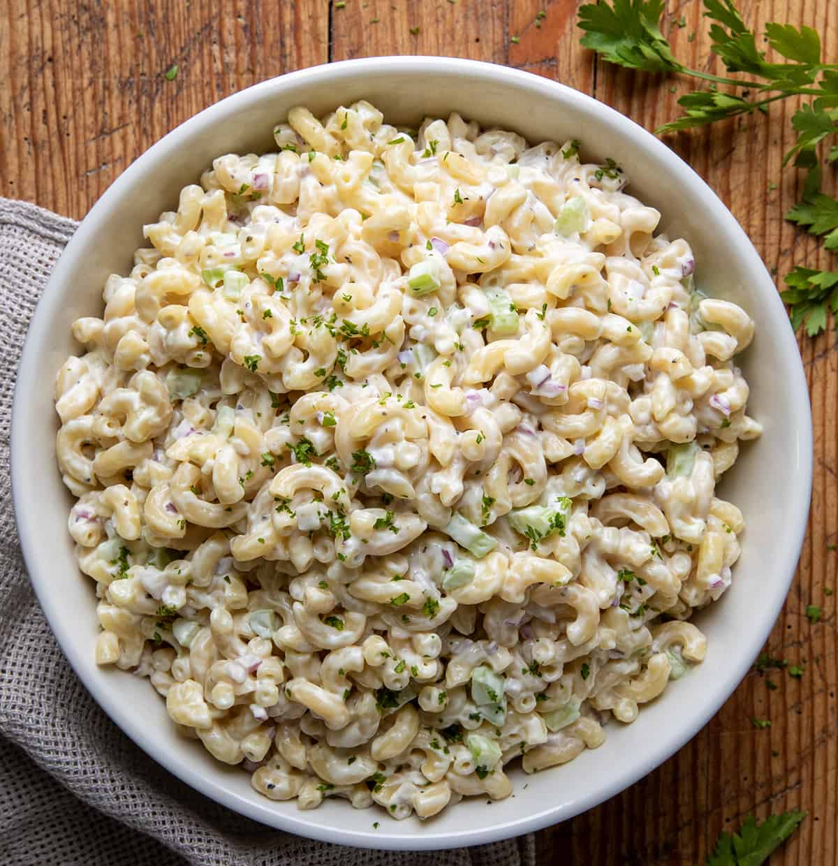 Macaroni Salad is a classic creamy pasta salad with sweet and tangy flavors, perfect for picnics, barbecues, or any time you need a side dish. It is a well-rounded salad with plenty of flavor and texture in every bite! Macaroni Salad in a big white bowl on a wooden table.