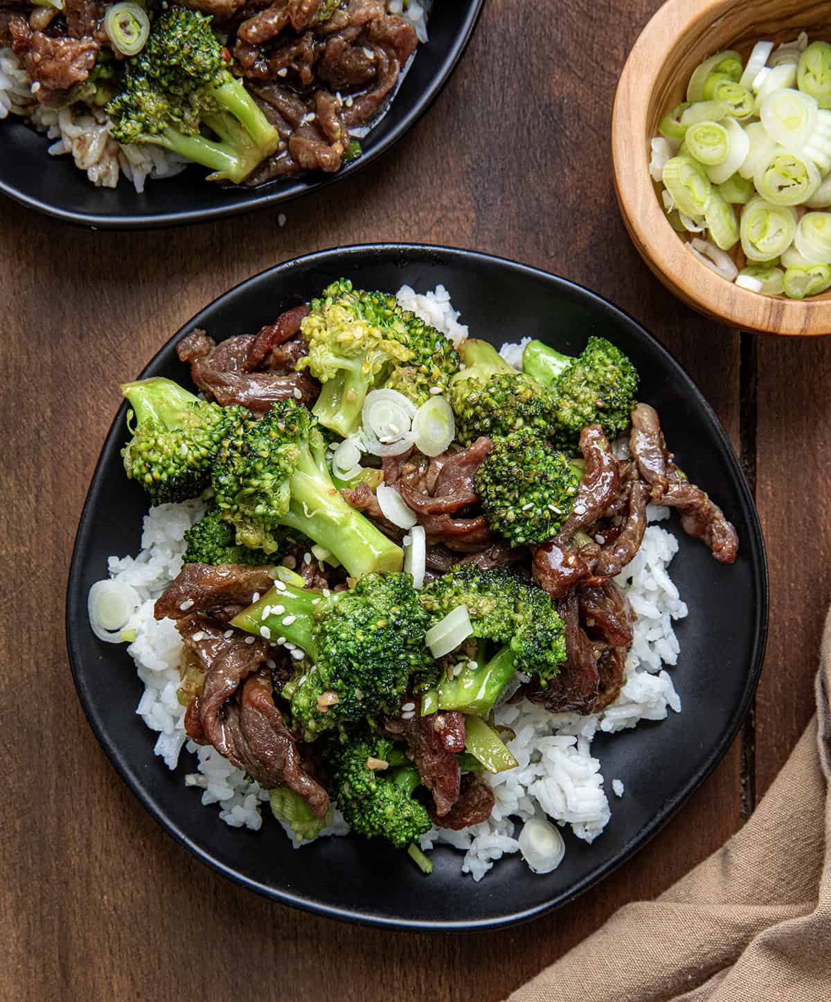 Plates of Beef and Broccoli on a wooden table from overhead.