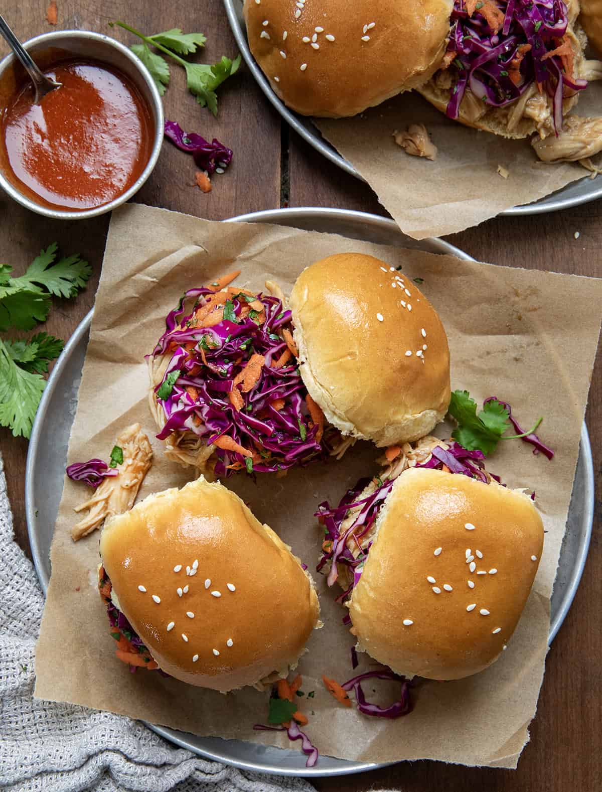 Three Honey Garlic Chicken Sliders on a plate on a wooden table.