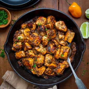 Skillet of Jerk Salmon Bites with a spoon in the skillet from overhead.