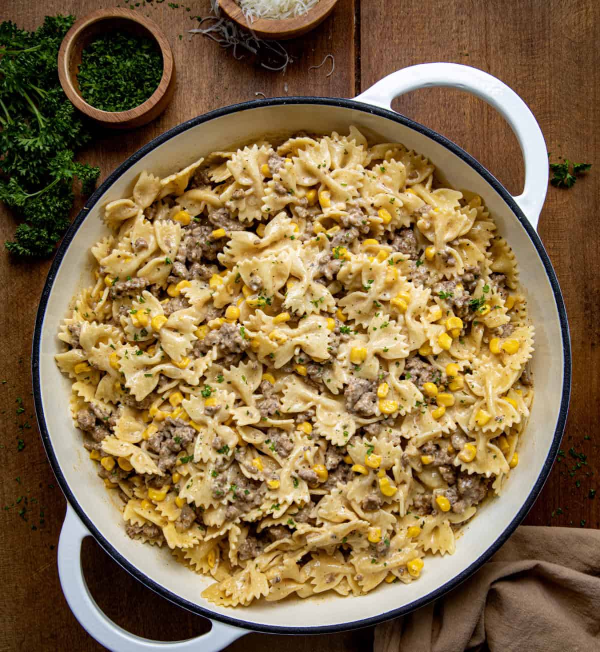 Savor the delicious Creamy Ranch Beef Pasta, a comforting dish with ground beef, corn, and a rich, creamy ranch sauce! Skillet of Creamy Ranch Beef Pasta on a wooden table from overhead.