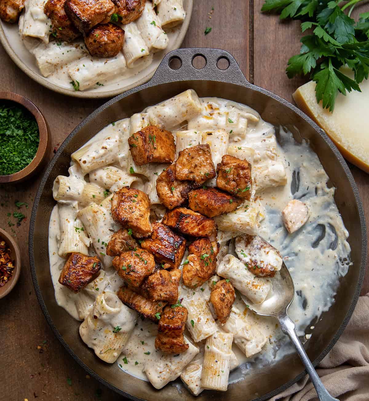 Skillet of Cajun Salmon Rigatoni with some removed and on a plate nearby.