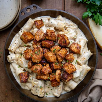 Skillet of Cajun Salmon Rigatoni on a wooden table from overhead.