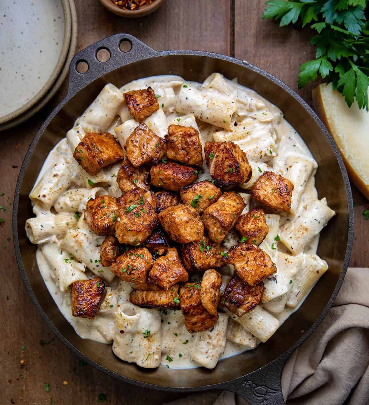 Skillet of Cajun Salmon Rigatoni on a wooden table from overhead. 
