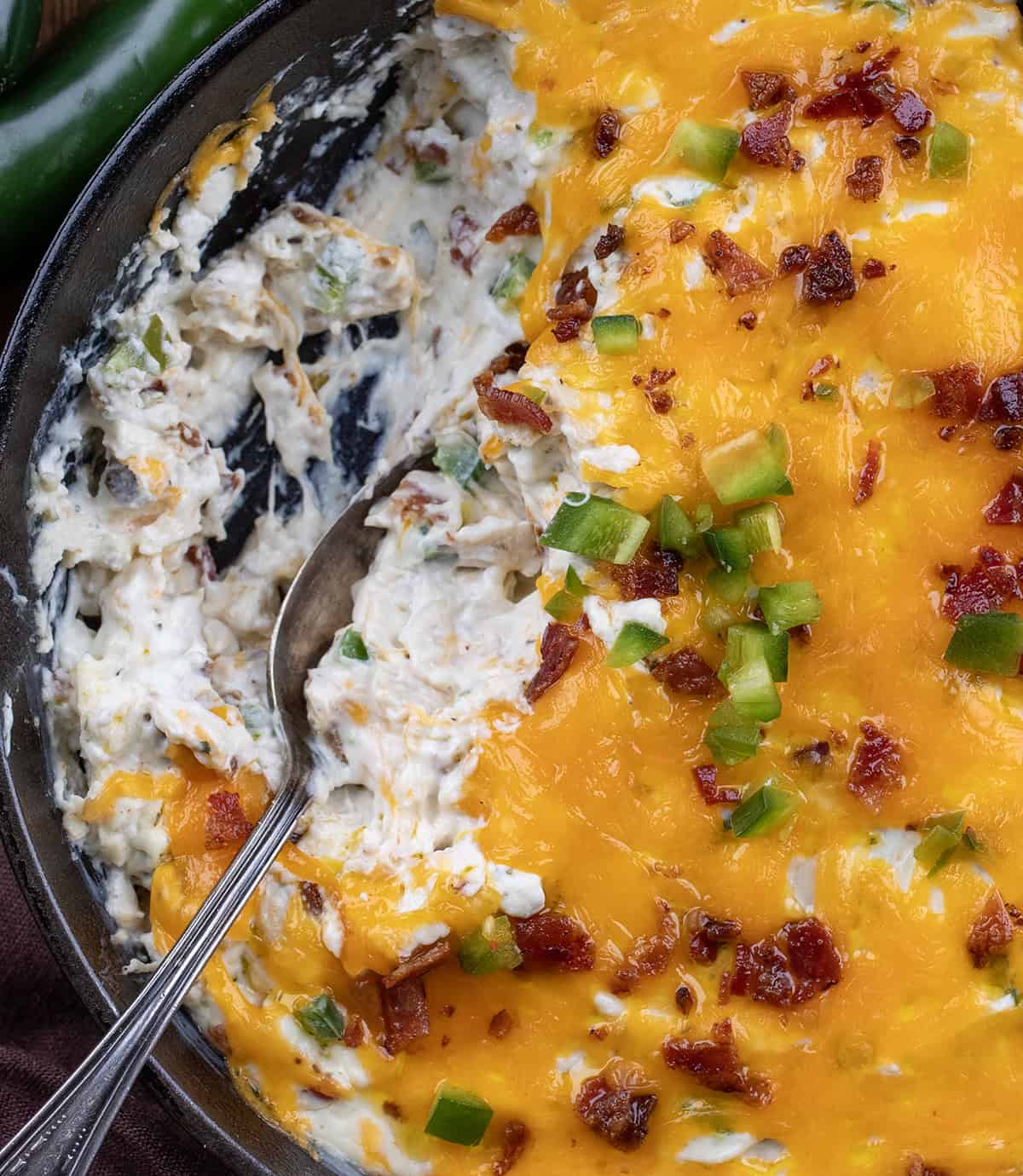 Chicken Jalapeño Popper Dip with some removed and a spoon in the skillet close up.