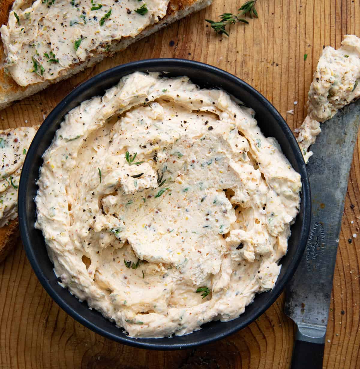 Bowl of Cowboy Cream Cheese on a wooden table with a knife and texas toast nearby.