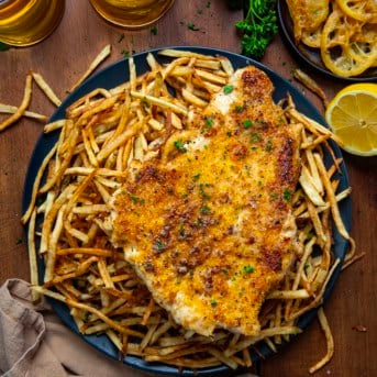 Plate of Chicken With A Thousand Fries on a wooden table from overhead.