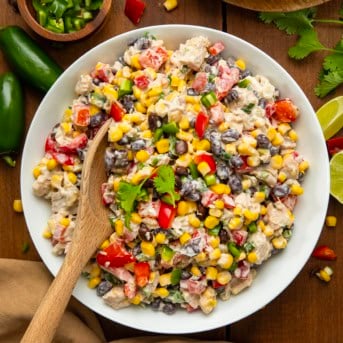 Bowl of Southwest Chicken Ranch Salad with a wooden spoon in it on a wooden table from overhead.